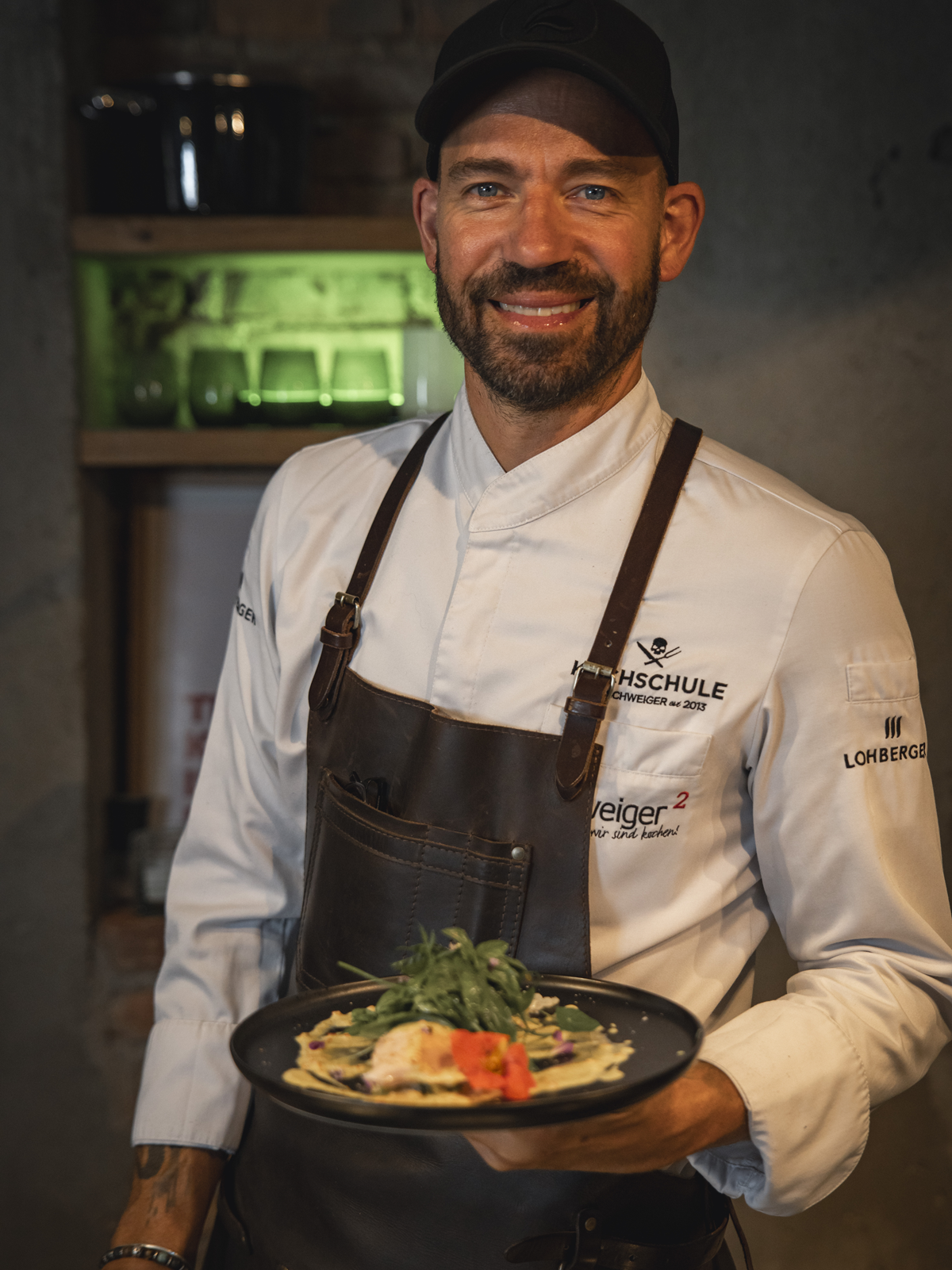 Profikoch Andi Schweiger mit einem fertigen Gericht in der Hand: Fisch Sous Vide | gebratener Blumenkohl | Curry Joghurt | Kräutersalat